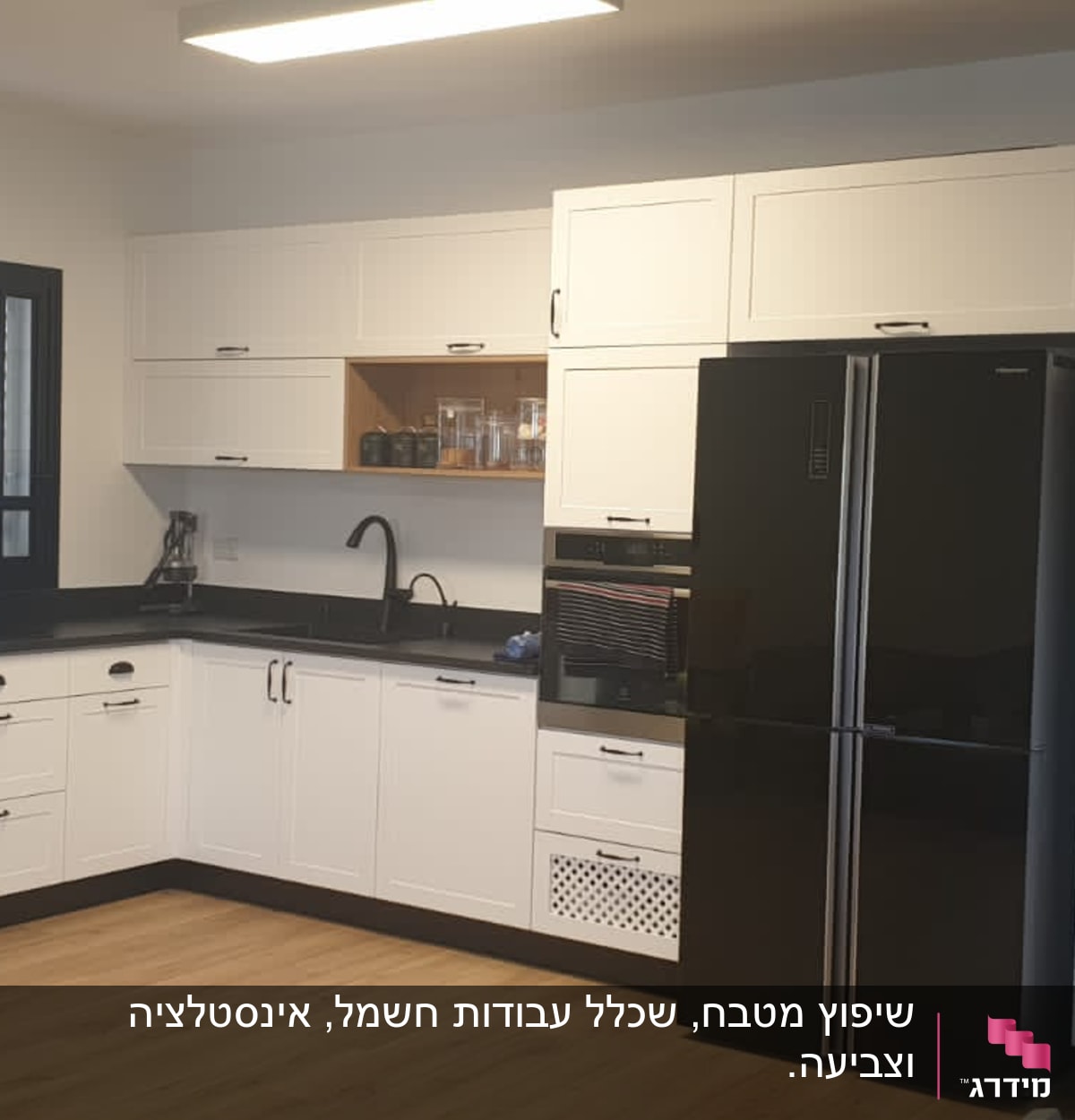 מטבח חדש עם ארונות לבנים ומקרר שחור